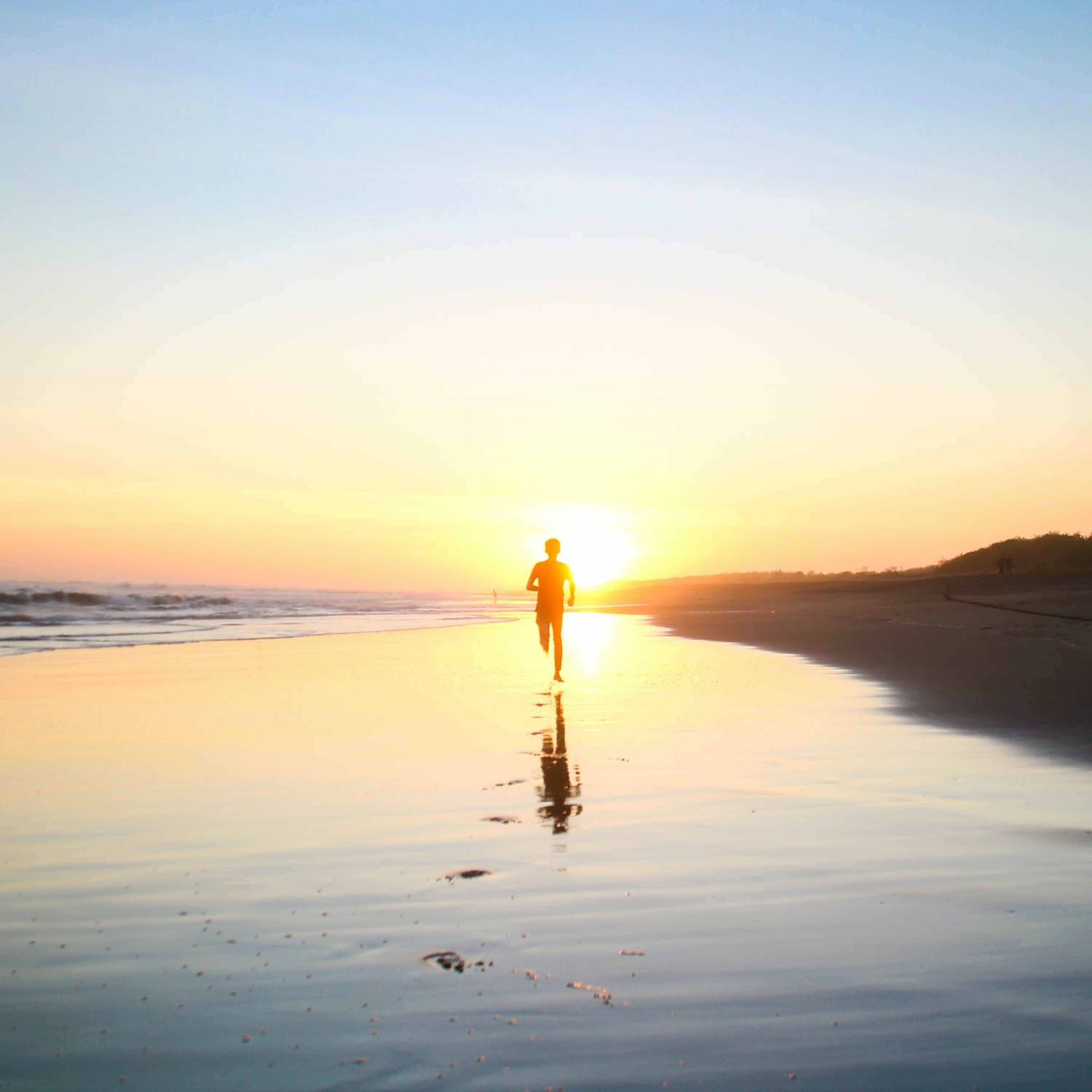 Man running on the beach during sunset 