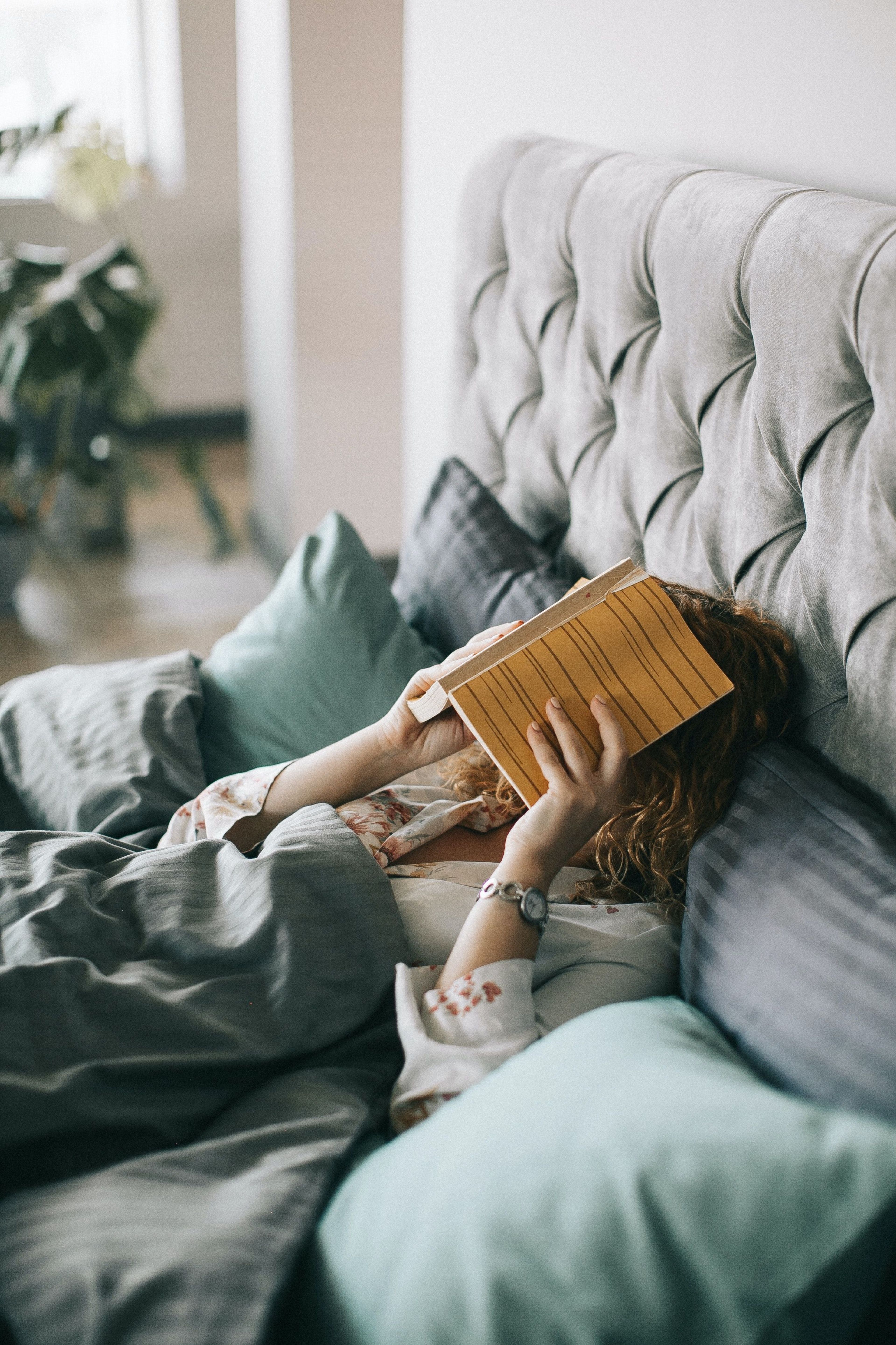 Woman in bed with a book over her face