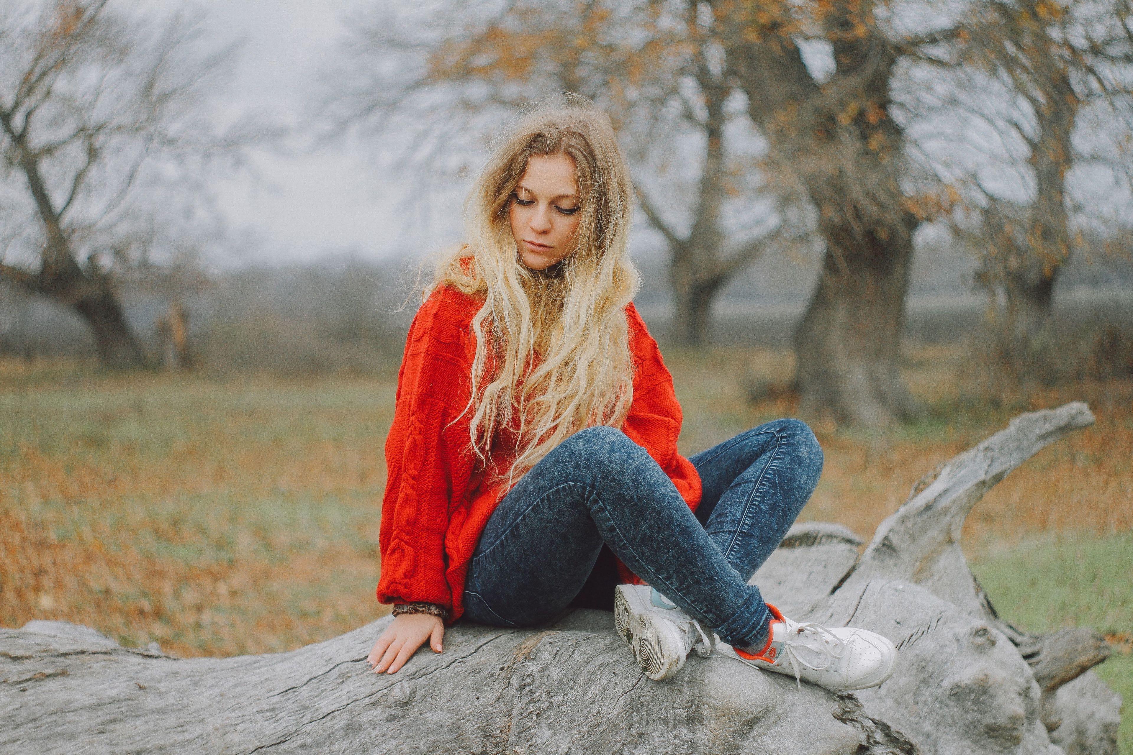 Girl in read sweater sitting on log