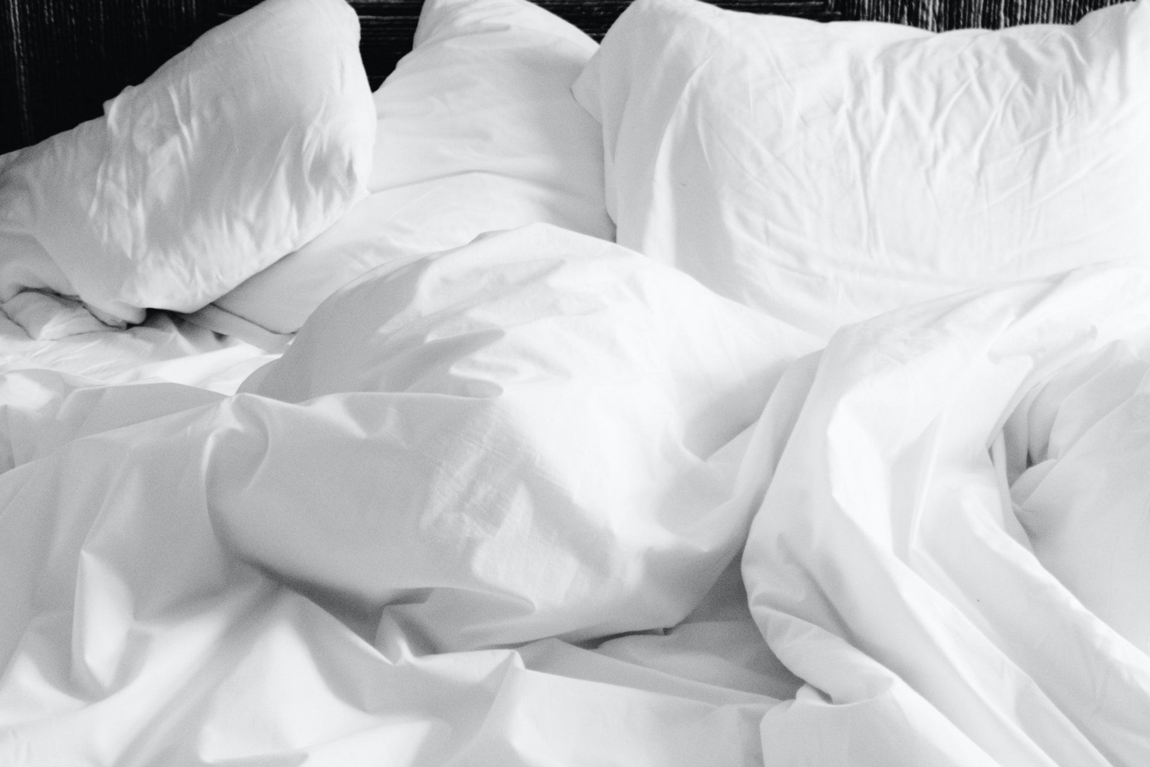 A white bed with large pillows and a blanket