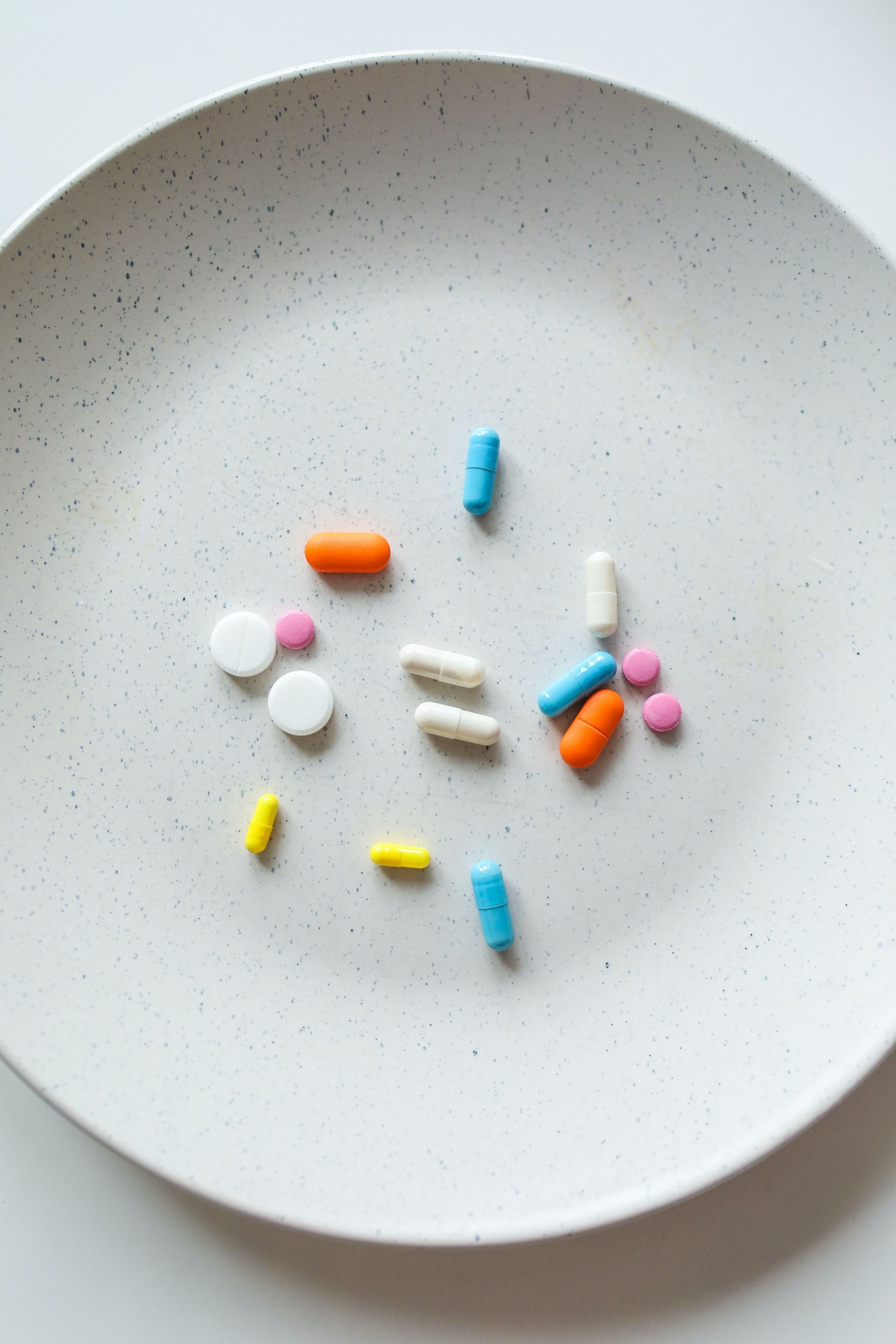 Several pills and medications on a white plate 