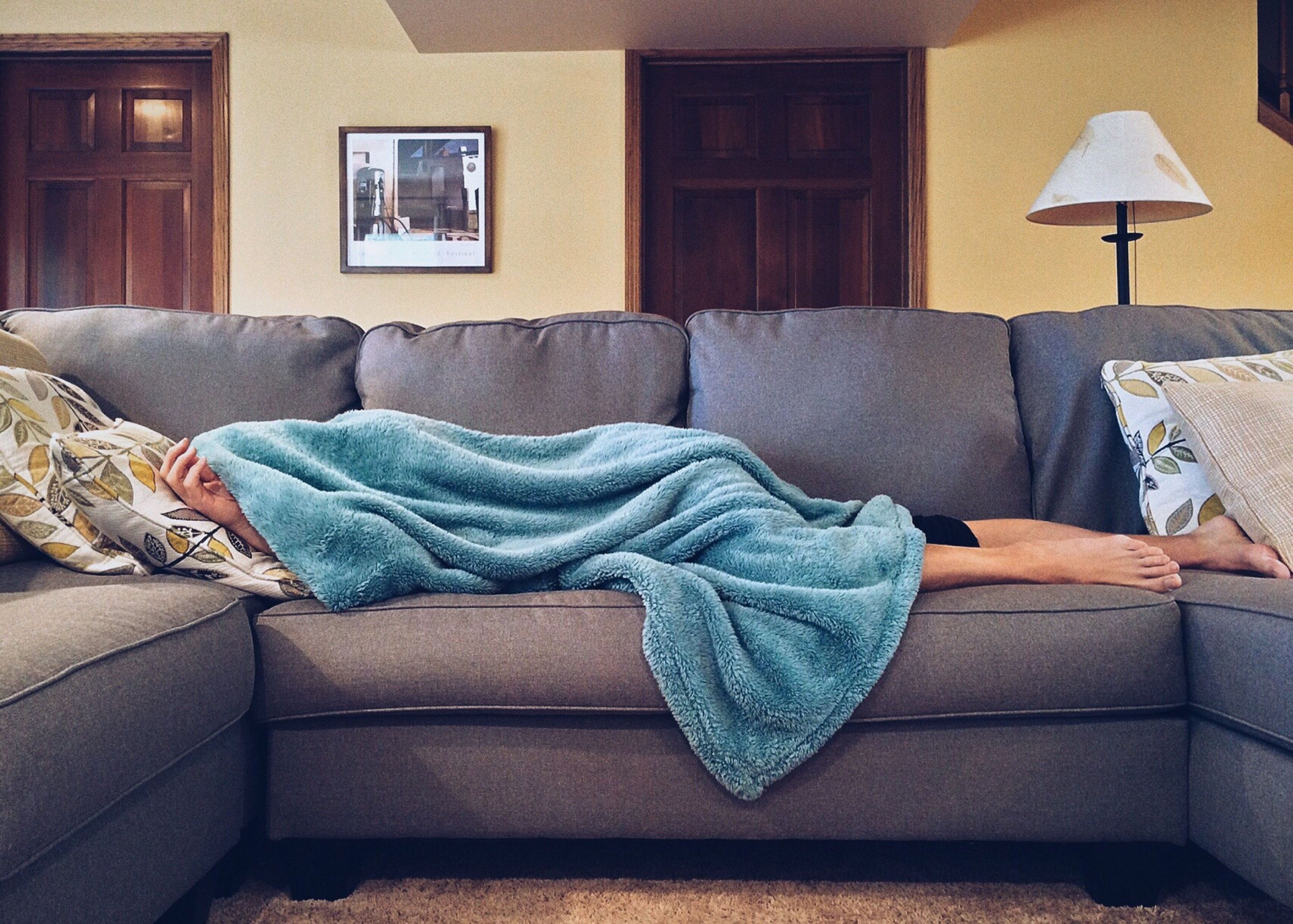 Women under blanket on couch with only hands and feet out