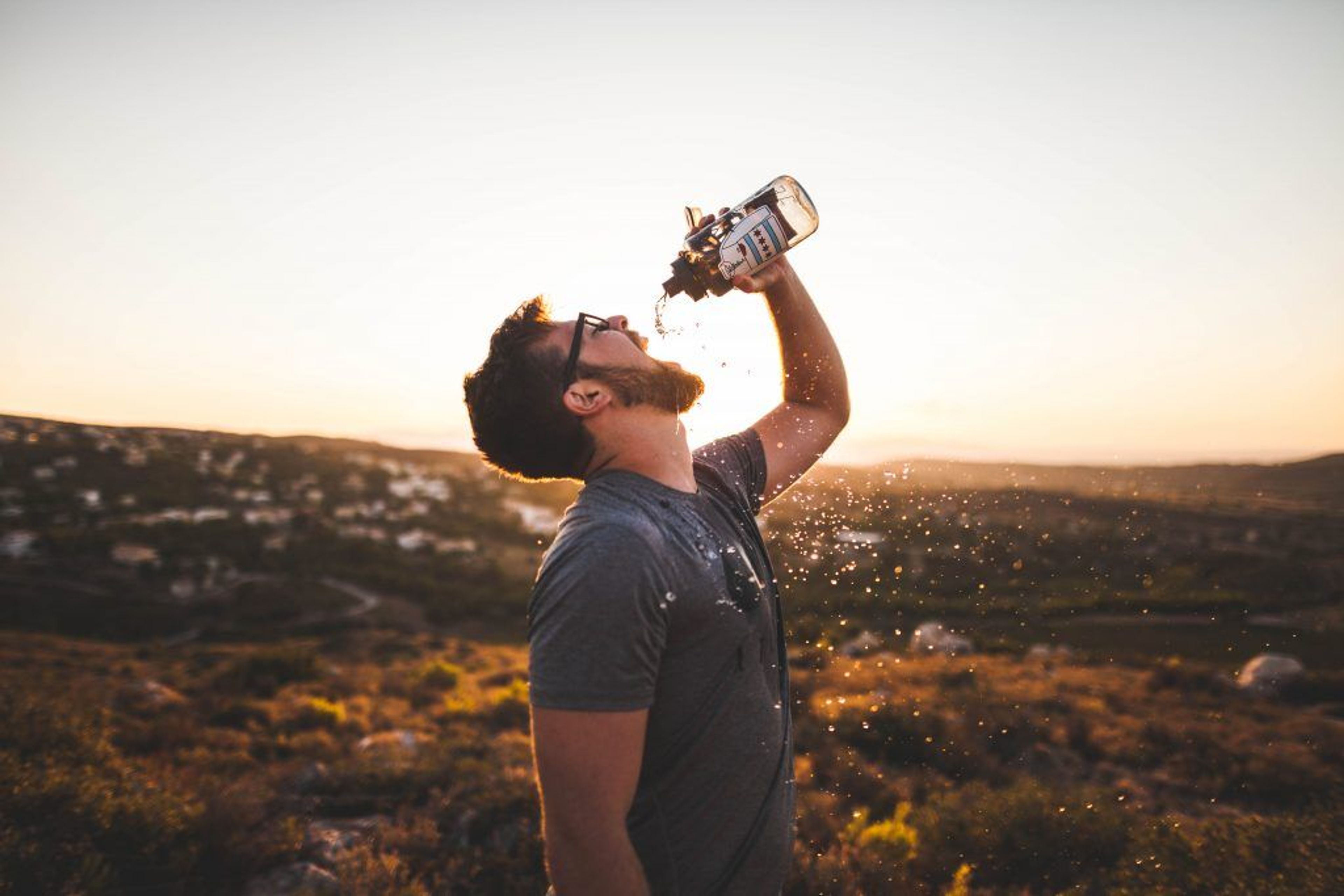 Man drinking water against the sunset 