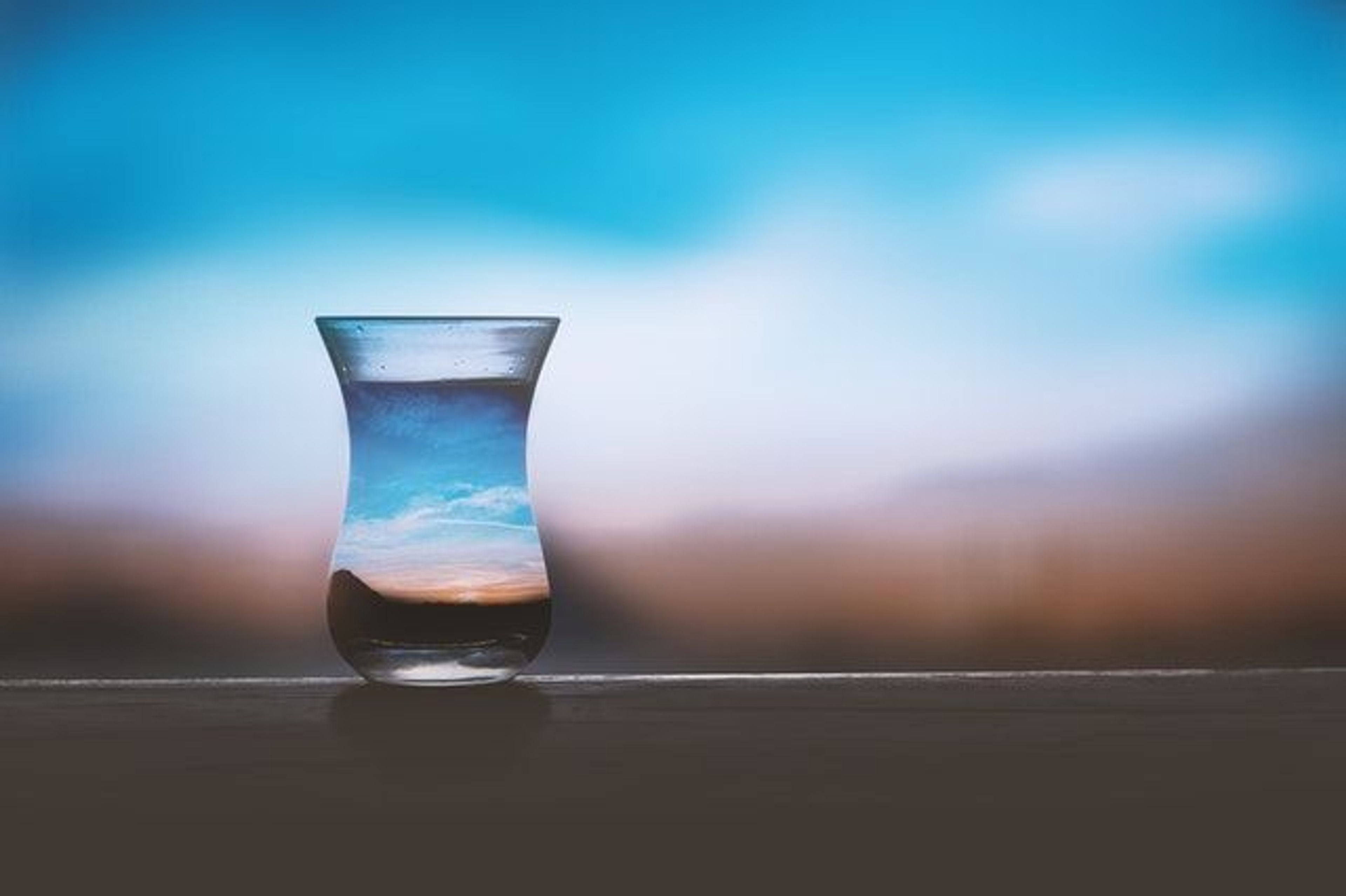 A glass of water with a sunset view behind it 